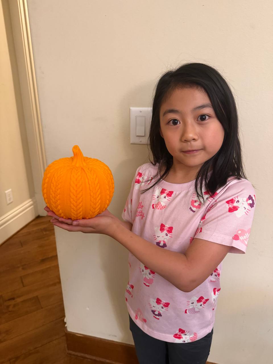 Girl holding bright orange cable-knit 3D printed pumpkin for size reference