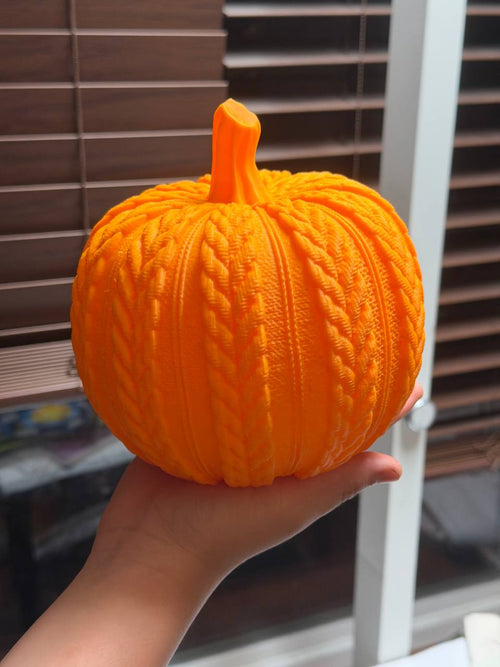 Bright orange 3D printed pumpkin with cable-knit texture held in hand